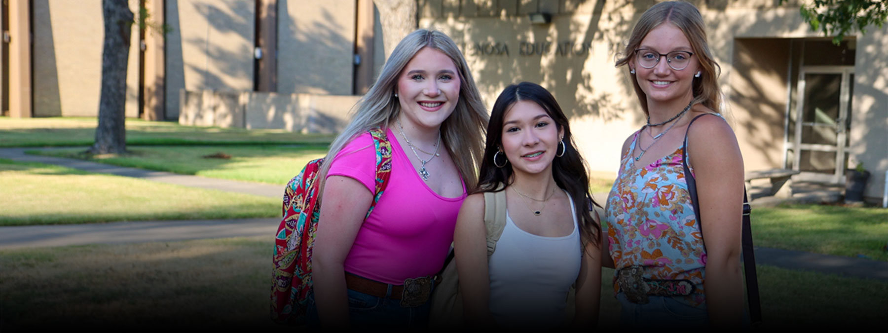 Picture of three students posing in front of the Espinosa Building of the Uvalde campus.